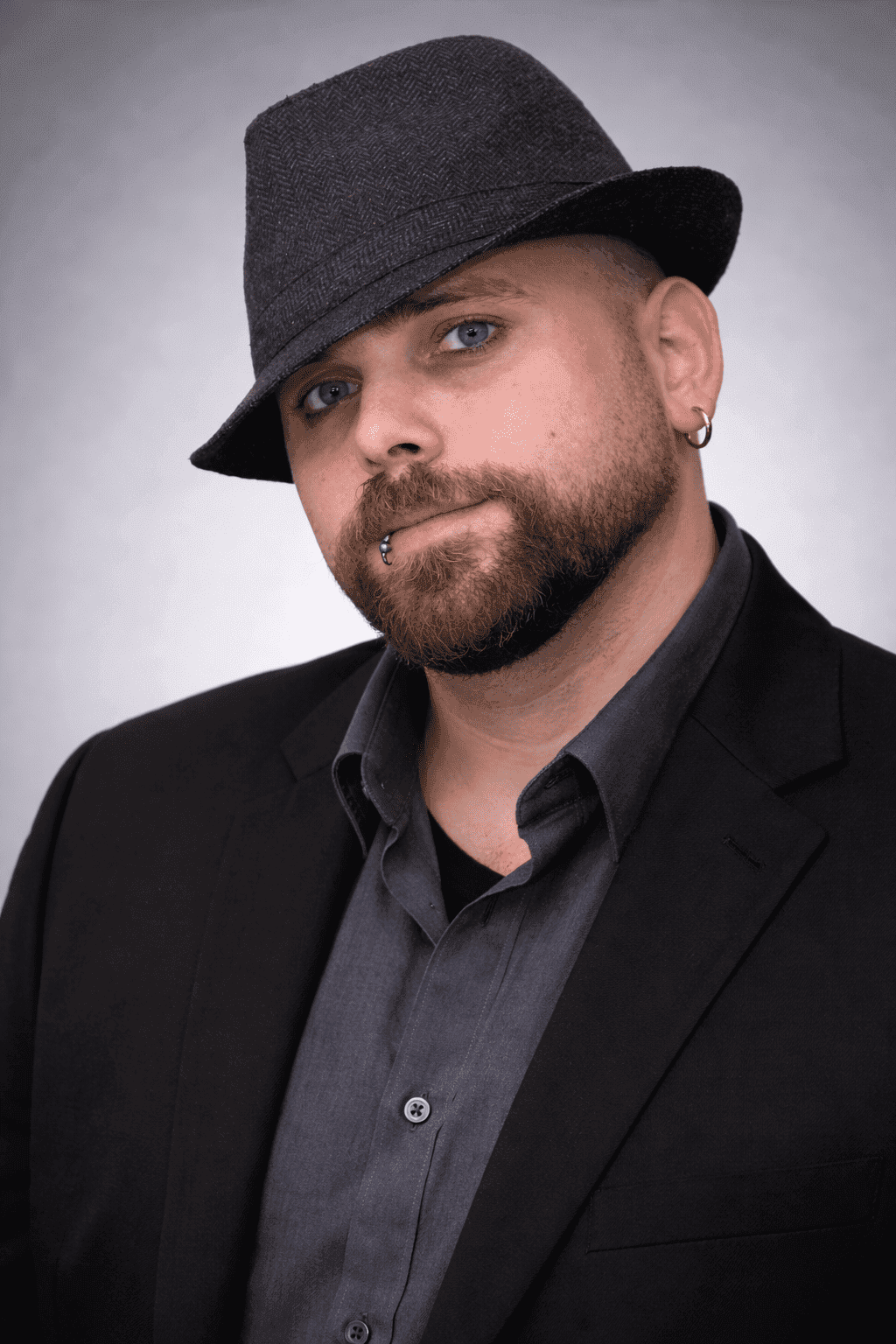 Man wearing a stylish hat and dark suit, representing professionalism and innovation in technology.